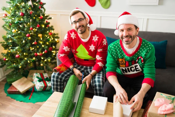 Cheerful Caucasian Gay Couple Wearing Christmas Pajamas Wrapping Family Friends — Stock Photo, Image