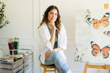 Beyaz tenli çekici kadın sanatçı bir resim yaptıktan sonra elinde fırça tutmaktan ilham alıyor.