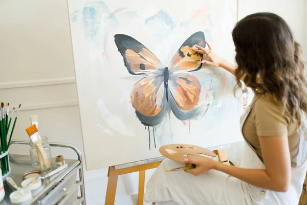 아름다운 나비를 캔버스에 그리기 팔레트와 손가락을 사용하여 뒤에서 여성화 — 스톡 사진
