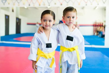 Tekvando ya da karate öğrenirken sarılıp gülümseyen sevimli bir oğlan ve kız.