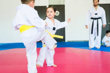 Dövüş sanatları okulundaki karate yarışması sırasında tekvando antrenmanı yapan aktif çocuklar.