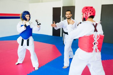 Yetişkin tekvando öğrencileri antrenman yapıyor ya da dövüş sanatları okulunda karate yarışmasına katılıyor.