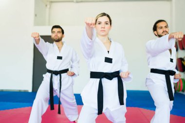 Genç kadın ve erkekler dövüş sanatları dersi sırasında tekvando ve antrenman yapıyorlar.