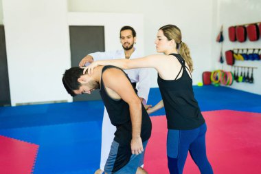 Yetişkin öğrenciler kişisel savunma öğreniyor ve dövüş sanatları dersinde pratik yapıyorlar.