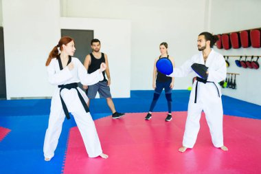 Karate koçu ve siyah kuşaklı genç bir kadın tekvando antrenmanına hazır.