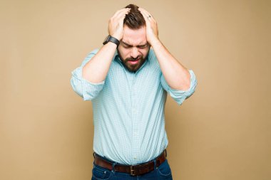 Stresli beyaz adam kafasına dokunuyor ve kötü bir migren veya baş ağrısı çekiyor. 