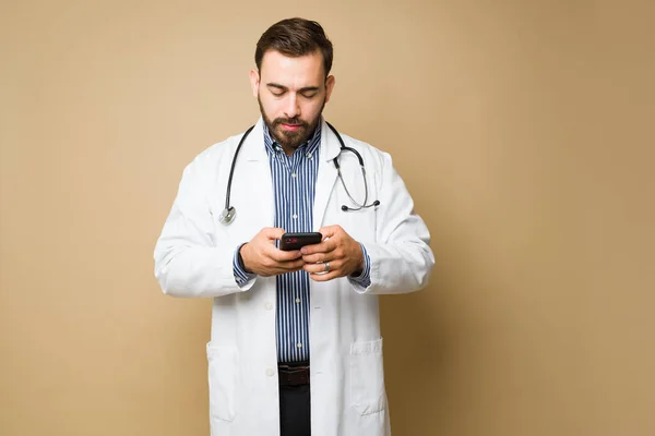 忙碌的男医生在医院工作时用智能手机发短信 — 图库照片