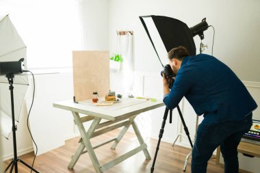 Fotoğrafçı stüdyosunda fotoğraf makinesi ve profesyonel kamera kullanarak yemek ürünü fotoğrafları çekiyor.