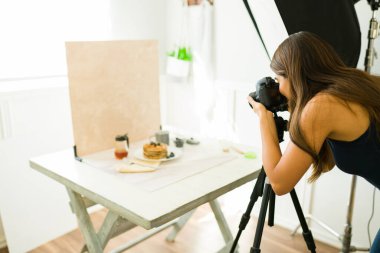 Profesyonel kadın fotoğrafçı stüdyosunda kamera ekipmanlarıyla fotoğraf çekiyor.
