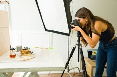 Profesyonel stüdyosunda yemek çekerken gülümseyen mutlu kadın fotoğrafçı.