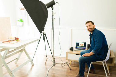 Beyaz fotoğrafçı stüdyodaki profesyonel çekimlerden sonra dizüstü bilgisayarda fotoğraf düzenleme yapıyor.