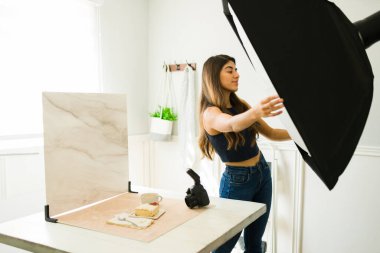 Profesyonel kadın fotoğrafçı ışıkları kuruyor ve yemek çekimi sırasında softbox kullanıyor.