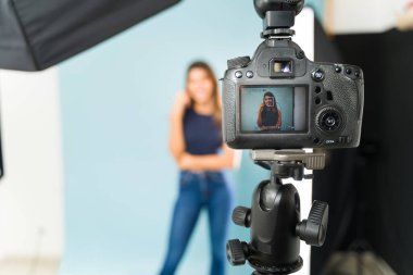 Fotoğraf stüdyosunda poz veren bir modelin fotoğraflarını gösteren profesyonel bir kamera.