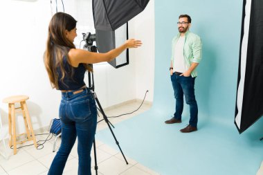 Moda fotoşopu sırasında beyaz bir erkek kaniş pozisyonuyla konuşan kadın fotoğrafçı.
