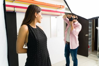 Çekici genç bir kadın model poz verirken bir fotoğrafçı stüdyoda profesyonel fotoğraflar çekiyor.