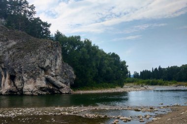 Ormanda mavi gökyüzüne karşı küçük bir dağ nehri.