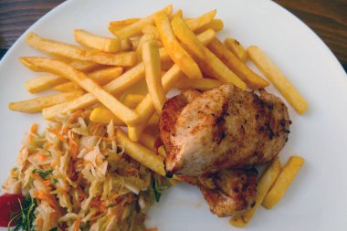 Tavuklu, patatesli ve salatalı bir tabağın üst görüntüsü.