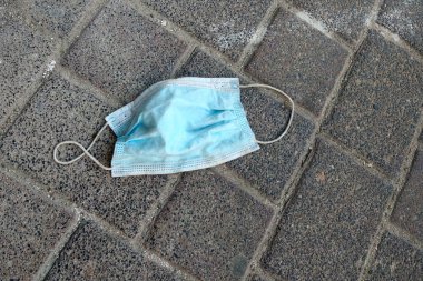 Kaldırımda tıbbi bir maske. Koronavirüse karşı maske kullanmak. COVID-19 'un yayılması. Yeni omikron damgası