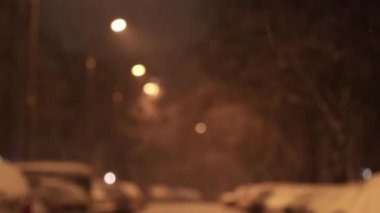 Odak dışı, bulanık arkaplan. Geceleri dışarıda kar yağar. Şehrin eski köyü. Şehirde karlı bir kış, film tahılları