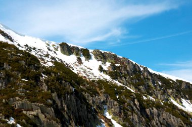 Dağın tepesinde kar, mavi gökyüzüne karşı uzanır.