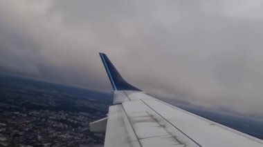 Bulutlu bir kış gününde şehrin üzerinde uçan bir uçağın penceresinden bak.