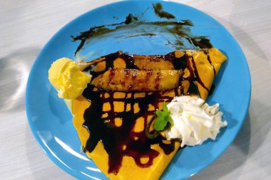 Tabakta çikolata ve dondurmalı leziz bir krep var.