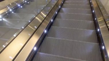 Asansörde aşağı doğru hareket var. Modern yürüyen merdiven. Gelecekteki boş merdivenler. Yürüyen merdivenler insanlar olmadan hareket ediyor.