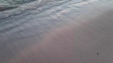 Deniz ya da okyanus kıyısında güzel kumlu bir sahil. Gün batımında dalgalar kıyıya vurur.