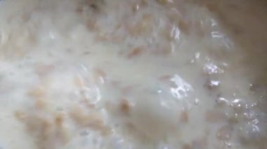 Close-up on cooking oatmeal with milk. Stirring porridge with a spoon during cooking. Light and tasty breakfast. Healthy food