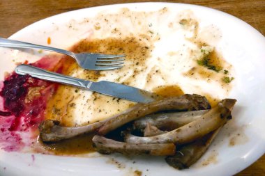 Yemekten sonra kirli çatal, kaşık ve kemik dolu bir tabak.