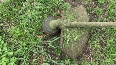 Fırça kesici, budama makinesi çimleri yakın plan biçer. Çim biçme makinesi yeşil çimlerin üzerinde yatıyor. Kopyalama alanı