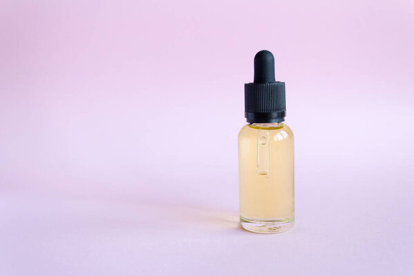 Aroma oil in a glass bottle. drip glass bottle with oil on pink background