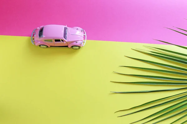 Palm leaf and toy car background with copy space. Background for writing text about traveling by car. Conceptual idea for website header and article writing.