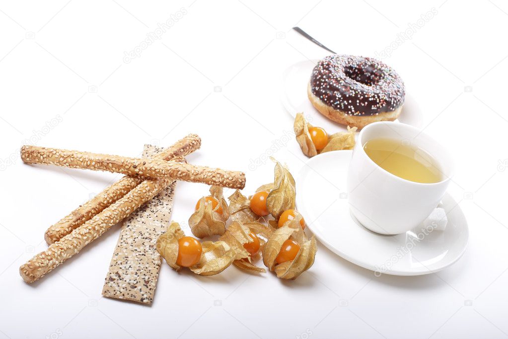 Tea cups with physalis, chocolate donuts and sesame cookies
