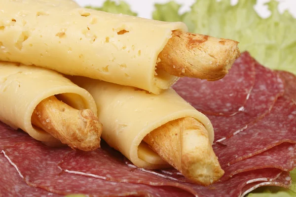 Salty cheese sticks with salami on lettuce — Stock Photo, Image
