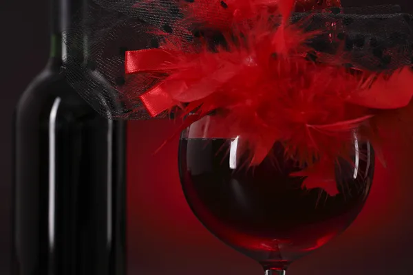 Glass of red wine with a feather hat — Stock Photo, Image
