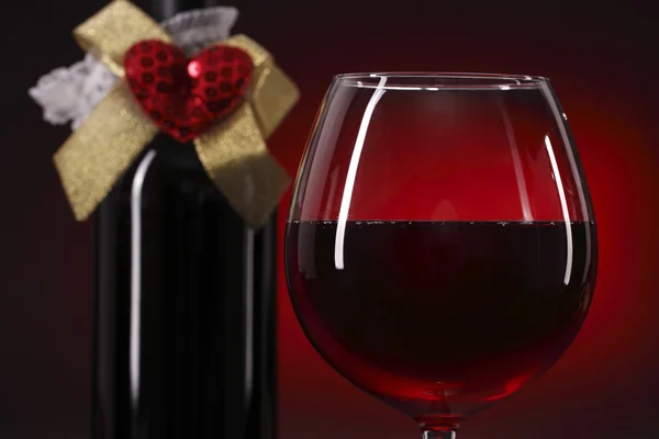 Copa de vino tinto y botella con corazón — Foto de Stock