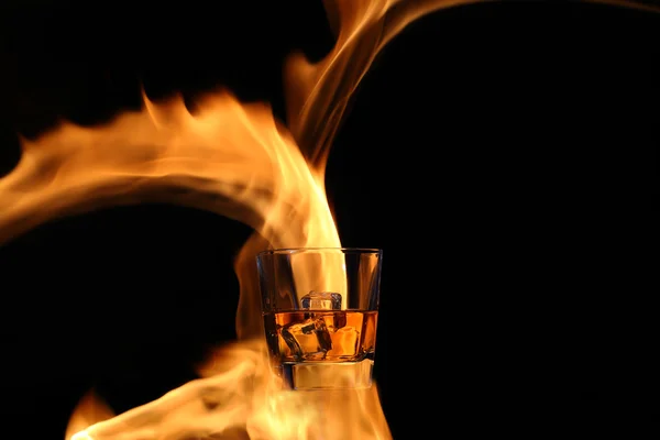 Glass with whiskey in the fire — Stock Photo, Image
