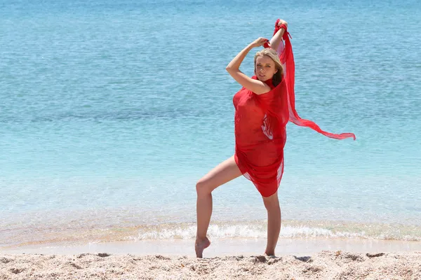 Mujer joven en rojo en la playa — Foto de Stock