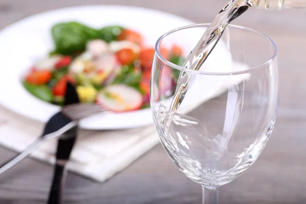 Pouring white wine into glass and food background — Stock Photo, Image