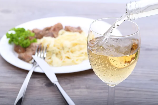 Pouring white wine and food background — Stock Photo, Image