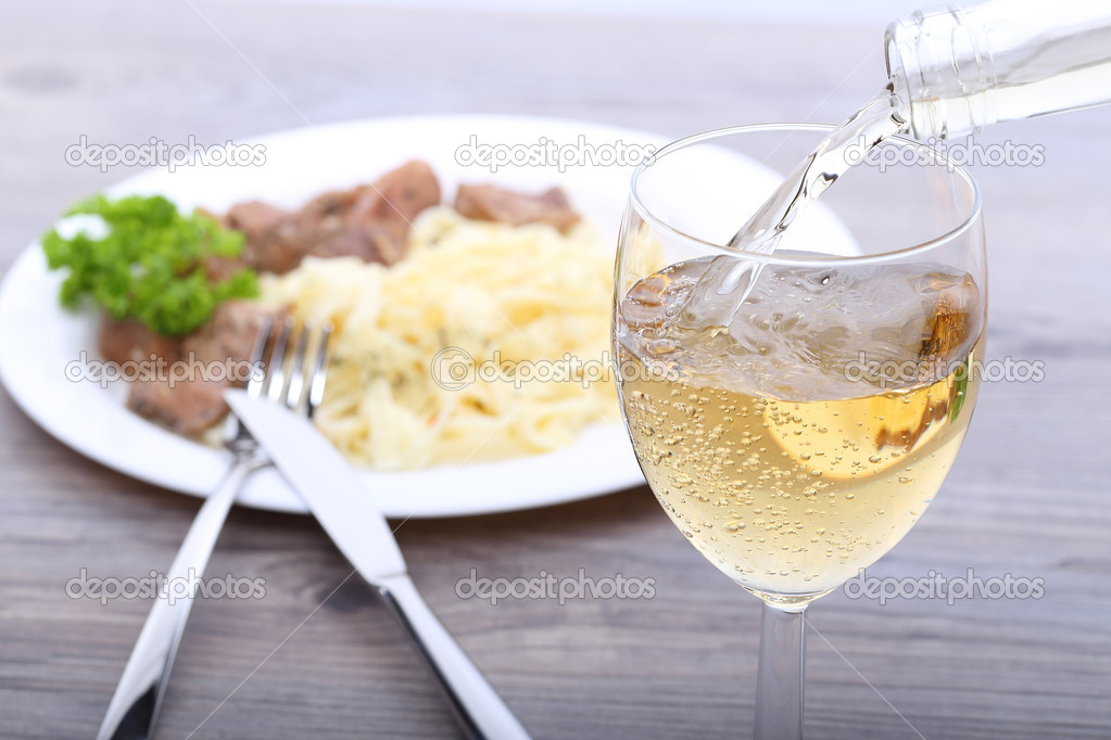 Pouring white wine and food background