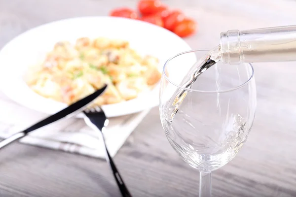 Pouring wine and pasta with salmon — Stock Photo, Image