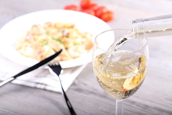 Pouring wine and pasta with salmon — Stock Photo, Image