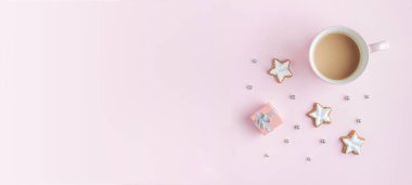 Kış sezonu pembe arka plan ve fotokopi alanı. Sıcak sütlü kupa, yıldız şeklinde zencefilli tarçınlı kurabiye, küçük hediye kutusu.. 