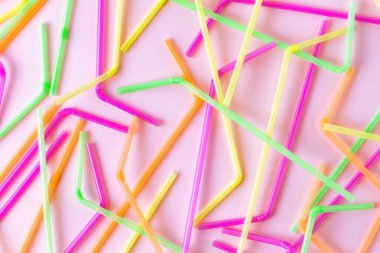 Pembe arka planda renkli neon plastik pipet kalıpları. Üst görünüm parlak renkli parti ögeleri