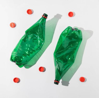 İki boş plastik şişe ve kırmızı kapağın üst görüntüsü. Tüketim ve çevresel sürdürülebilirlik kavramı.