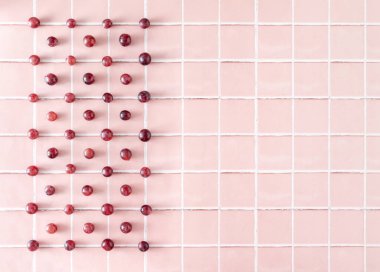 Red grapes pattern on pink tiles with copy space. Seasonal healthy berry fruit arranged in rectangular shape along parallel lines. 