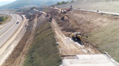 Bir otoyol yamacını tamir eden endüstriyel makineler. Kazıcılar yol kenarını koruyor.