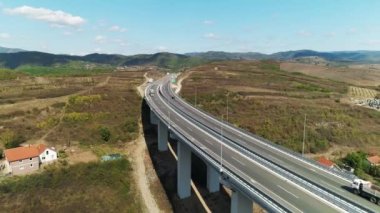 Viyadük köprüsü, düşük trafik, kamyon geçiyor. Hava aracı güneşli bir günde vuruldu. Güney Sırbistan 'daki viyadük köprüsünde trafik düşük. Birkaç araba ve bir kamyon geçiyor. Hava aracı atışı. Skyline, tepeler. Parlak güneşli bir gün.